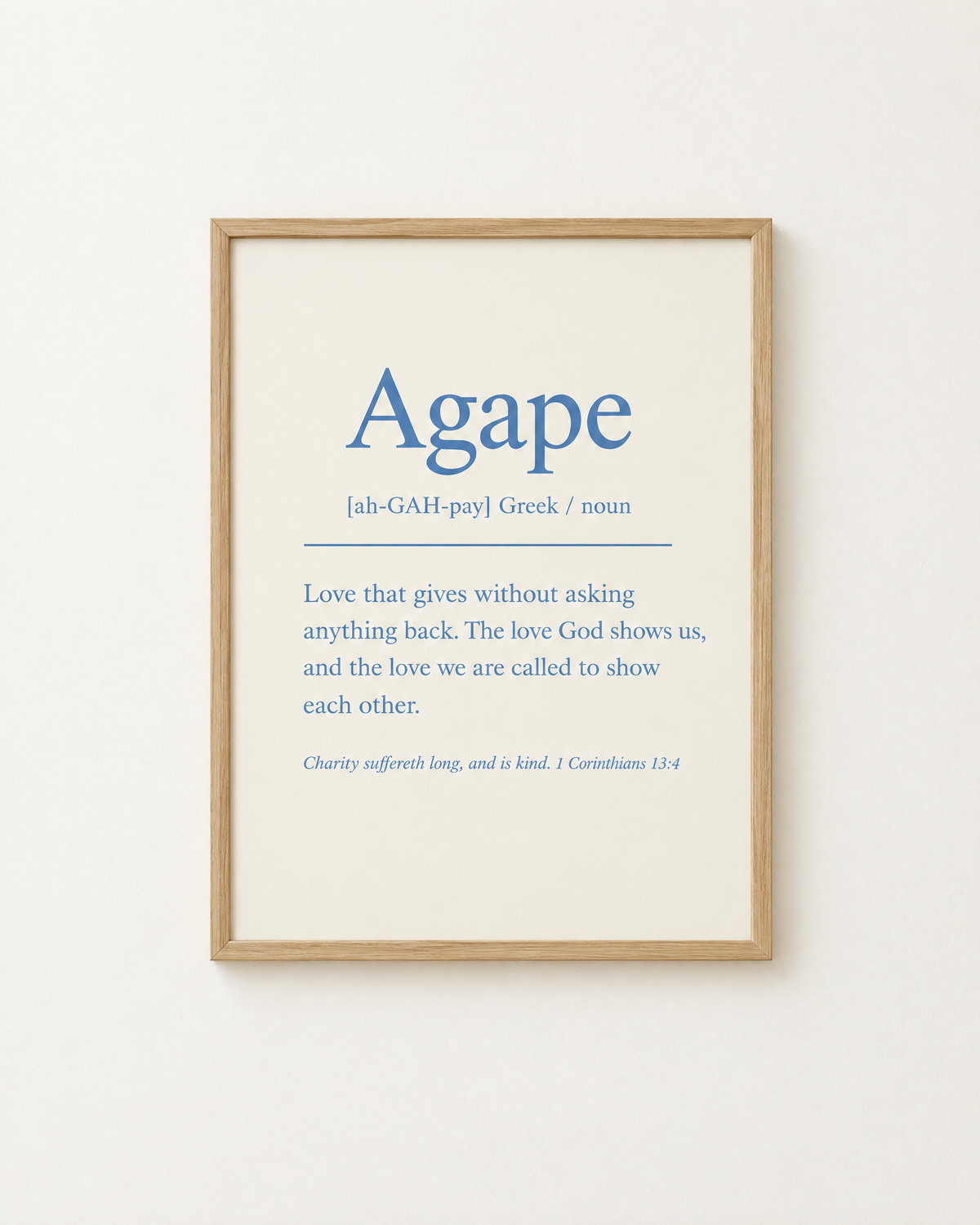 Agape: Dusty Blue print in an oak frame on a white wall, reading “Charity suffereth long, and is kind” (1 Corinthians 13:4, KJV). Digital mockup.