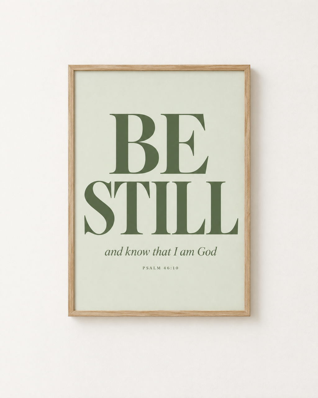 Be Still: Sage print in an oak frame on a white wall, reading “Be still, and know that I am God” (Psalm 46:10, KJV). Digital mockup.