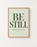 Be Still: Sage print in an oak frame on a white wall, reading “Be still, and know that I am God” (Psalm 46:10, KJV). Digital mockup.