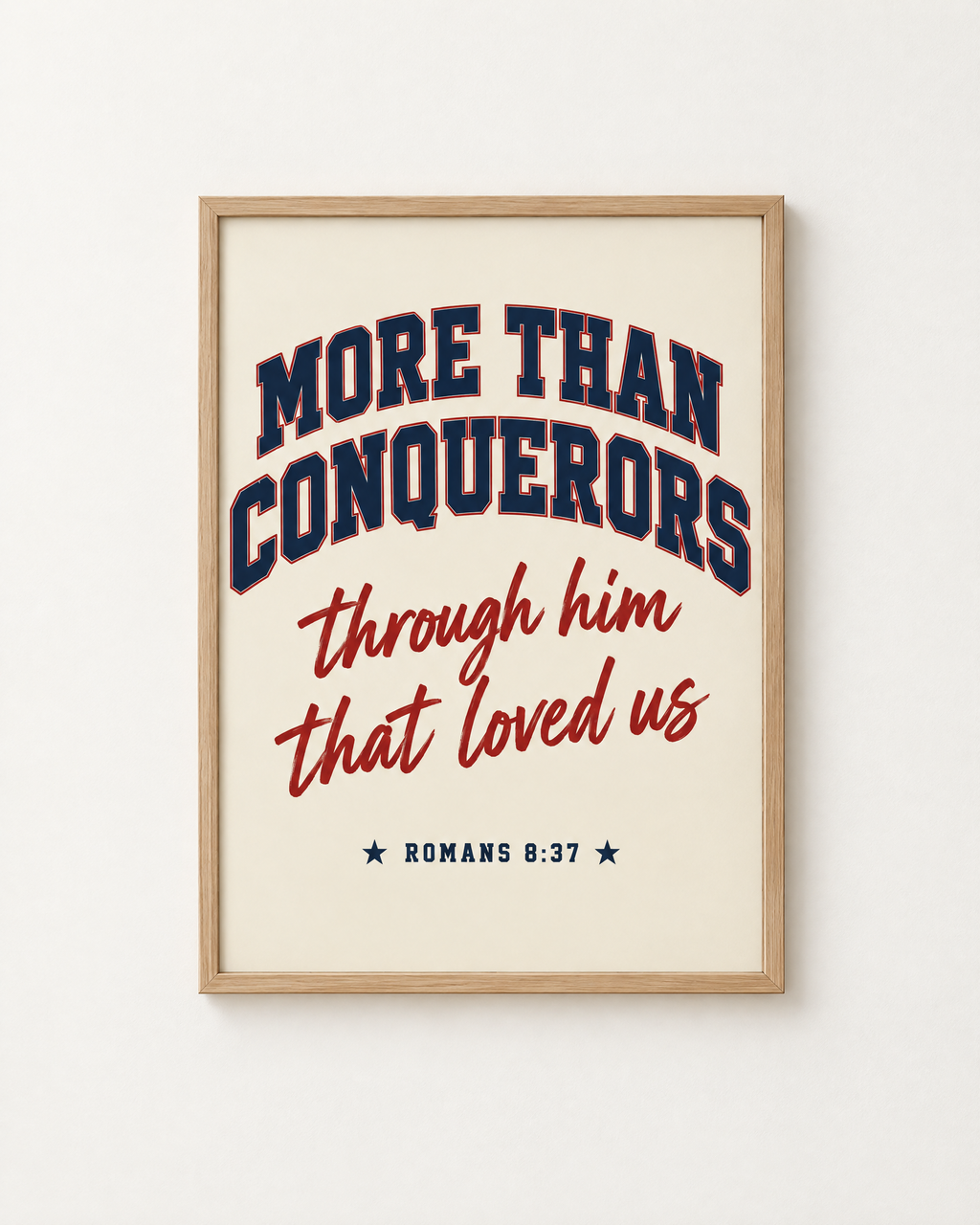 More Than Conquerors: Varsity print in an oak frame on a white wall, reading “More than conquerors through him that loved us” (Romans 8:37, KJV). Digital mockup.