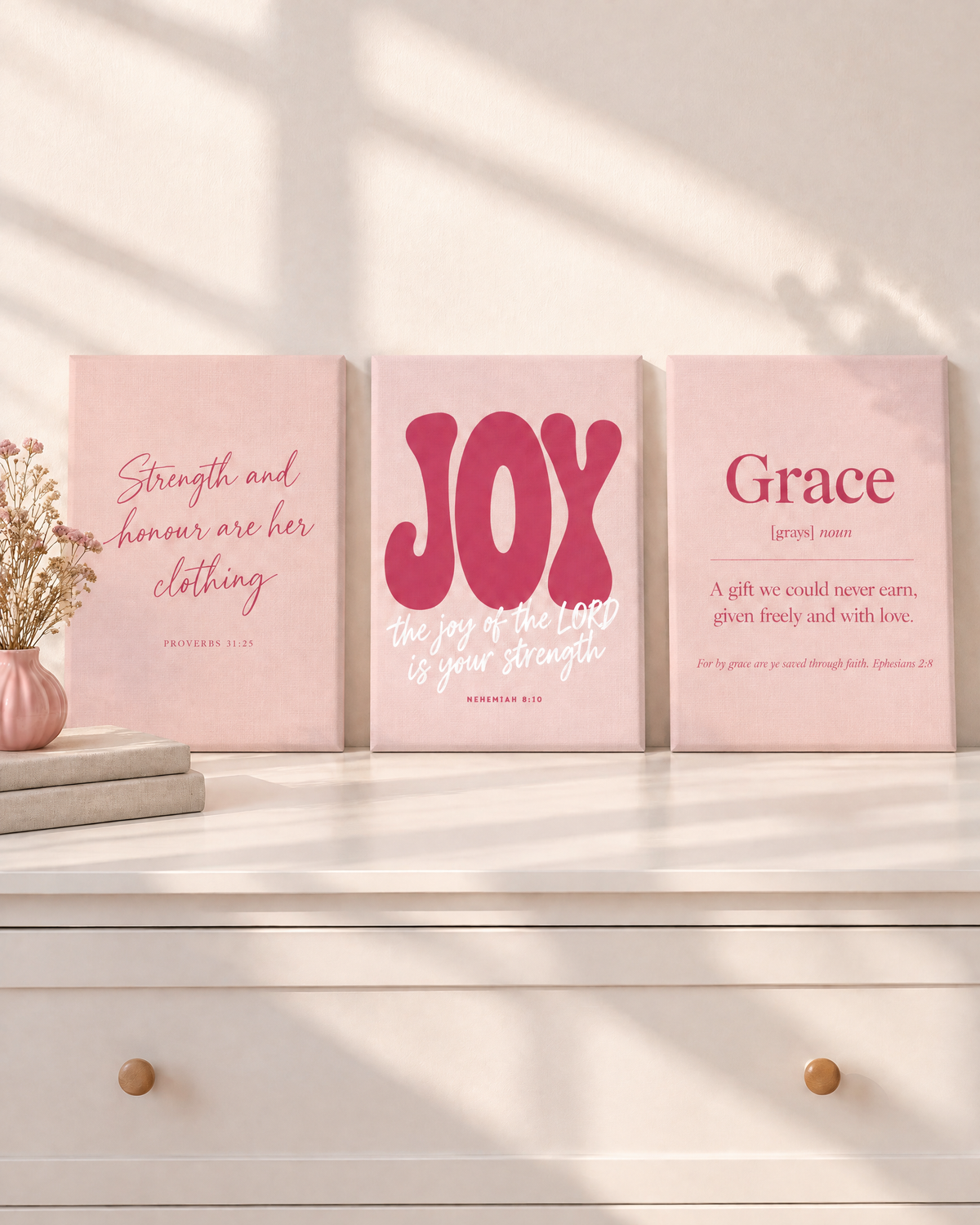 Digital mockup: the Blush Set of 3 as gallery-wrapped canvases on a white dresser: “Strength and honour are her clothing” (Proverbs 31:25), JOY “the joy of the LORD is your strength” (Nehemiah 8:10) and Grace (Ephesians 2:8).